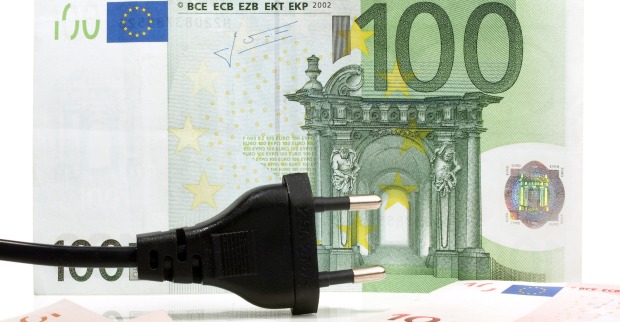 Ein schwarzer Stromstecker liegt vor einem 100-Euro-Geldschein – Symbolbild für Energiepreise und Rückerstattung.