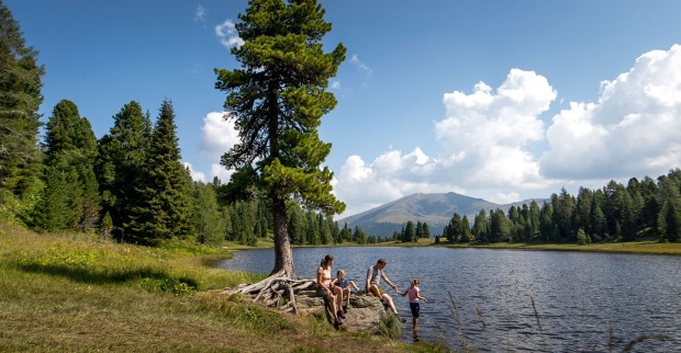 Familie am Ufer eines Waldsees | Credit: Holzwelt Murau/Tom Lamm