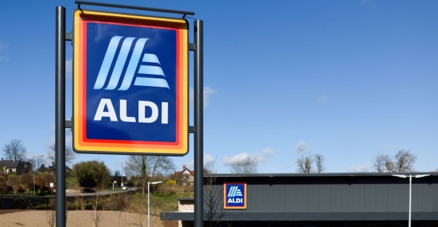Aldi-Logo auf einem großen Schild vor einer Filiale bei blauem Himmel.