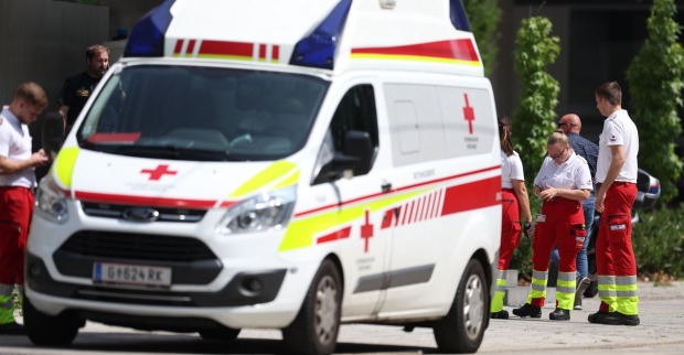 Sanitäterinnen und Sanitäter des Roten Kreuzes sowie Polizeibeamte stehen neben einem Rettungswagen im Einsatzgebiet nach dem Amoklauf in Graz.
