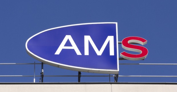 Logo des Arbeitsmarktservice (AMS) auf einem Gebäudedach vor blauem Himmel, das rote S am rechten Rand leuchtet.