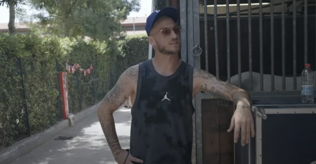 Marko Arnautović mit Sonnenbrille und blauer Kappe in einem Pferdestall, leicht lächelnd, im Hintergrund Holzstallwände und Grün.