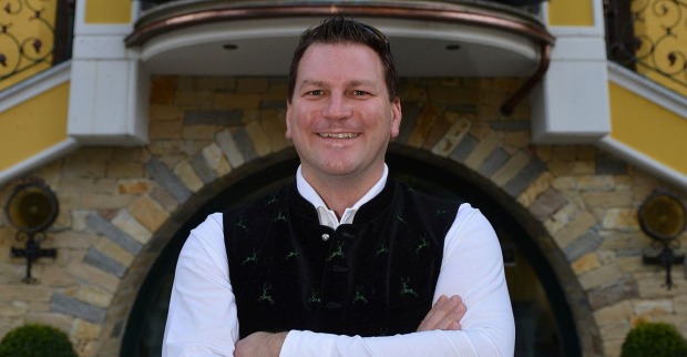 Hotelier Christian Steiner steht lächelnd mit verschränkten Armen vor seinem Hotel