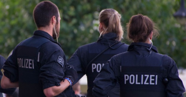 Drei Polizist:innen von hinten in Einsatzkleidung bei einem Einsatz im Freien