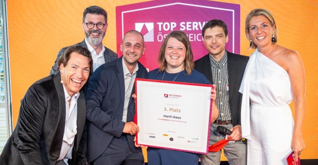 Sechs fröhliche Personen mit Urkunde bei der Top Service Österreich-Verleihung