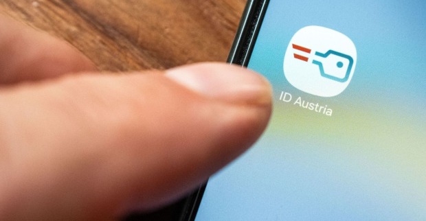 Smartphonedisplay, welches die "ID Austria" App anzeigt, Ein Finger klickt darauf
