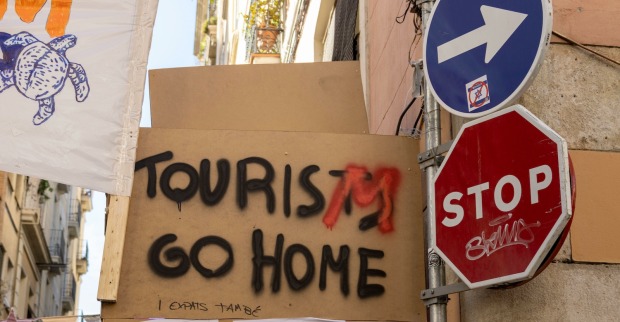 Protestplakat mit der Aufschrift „Tourists go home“ und Stoppschild in Barcelonas Altstadt