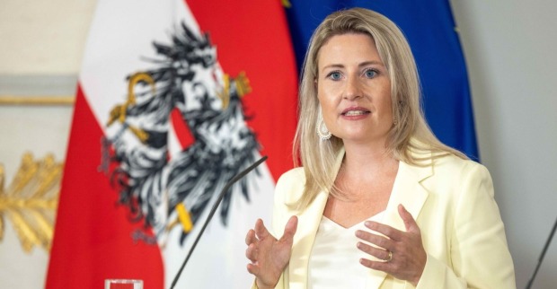 Susanne Raab spricht bei einer Pressekonferenz, im Hintergrund die österreichische und die EU-Flagge.