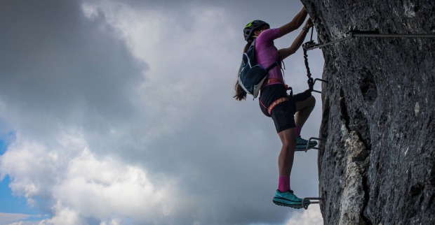 Eine Frau klettert auf einem Klettersteig.