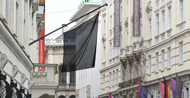 Schwarze Trauerfahne weht vor dem Globenmuseum in der Wiener Innenstadt. Rechts im Bild Hotel Steigenberger, mehrere Nationalflaggen, darunter EU- und Österreich-Flagge, hängen auf Halbmast.