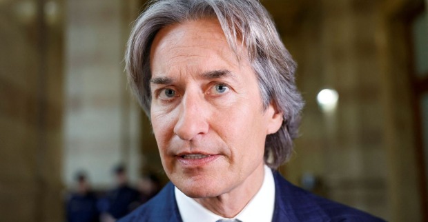 Porträt von Karl-Heinz Grasser im Anzug, aufgenommen in einem Gerichtsgebäude. Der ehemalige österreichische Finanzminister blickt ernst in die Kamera.