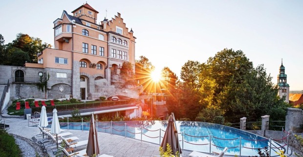 Hotel Schloss Mönchstein mit Infinity-Pool im Sonnenuntergang, Blick auf die Stadt Salzburg und den Mönchsberg