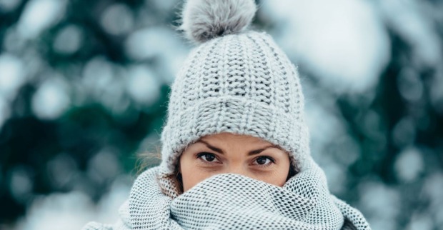 Junge Frau in Winterbekleidung steht vor verschneiten Bäumen