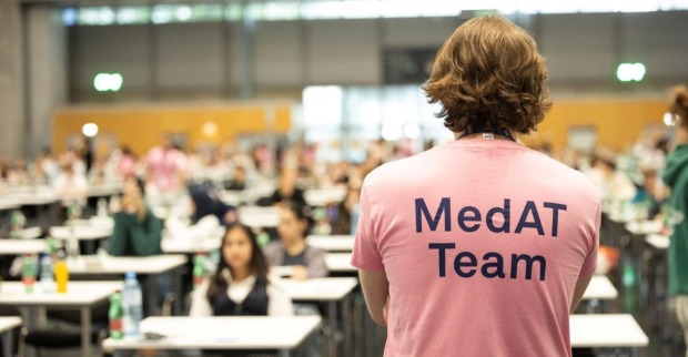 Mann steht in einem MedAT T-Shirt