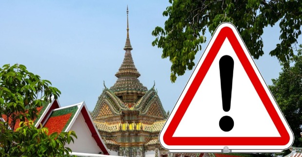 Warnschild mit Ausrufezeichen vor thailändischem Tempel – Symbolbild zur aktuellen Reisewarnung wegen des Konflikts zwischen Thailand und Kambodscha.