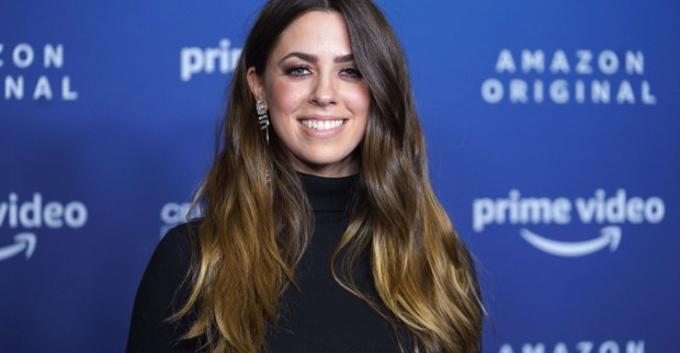 Vanessa Mai bei einer Amazon Prime-Premiere, schwarz gekleidet mit silbernen Ohrringen vor blauem Hintergrundit