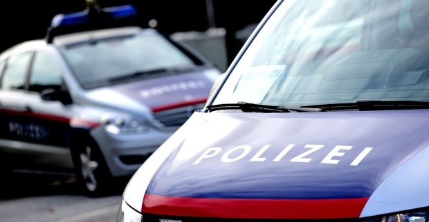 Zwei Polizeiwagen der Österreichischen Polizei stehen auf einer Straße im Tageslicht