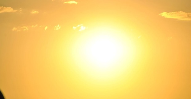 Grell strahlende Sonne am wolkenarmen Himmel, die intensive Hitze und sonniges Wetter andeutet.