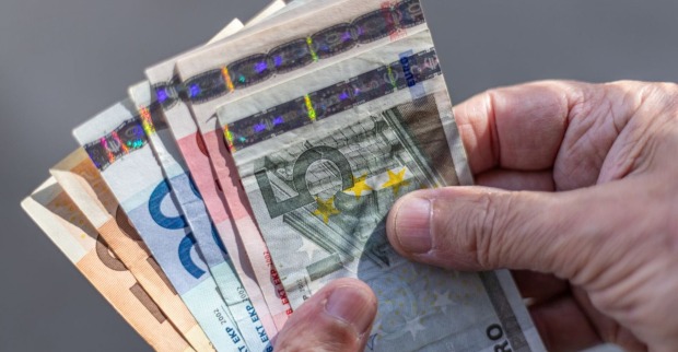 Alt-Text: Hände einer älteren Person halten mehrere Euro-Banknoten; symbolisch für Pensionen, Geldwert und soziale Absicherung im Alter.