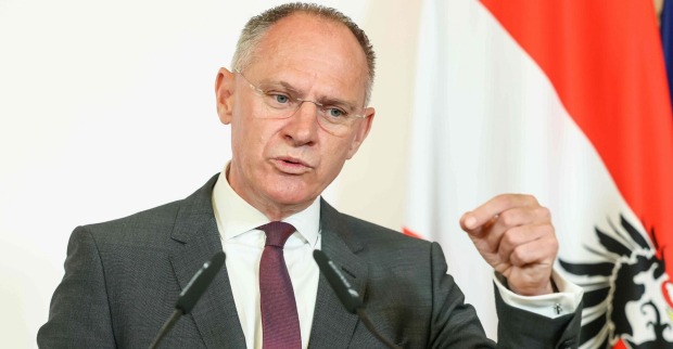 Gerhard Karner, österreichischer Innenminister, spricht bei einer Pressekonferenz vor Mikrofonen, im Hintergrund eine österreichische Fahne.