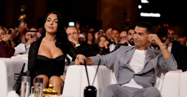 Cristiano Ronaldo und Georgina Rodríguez sitzen bei einer Gala nebeneinander, halten Händchen und präsentieren den funkelnden Verlobungsring.