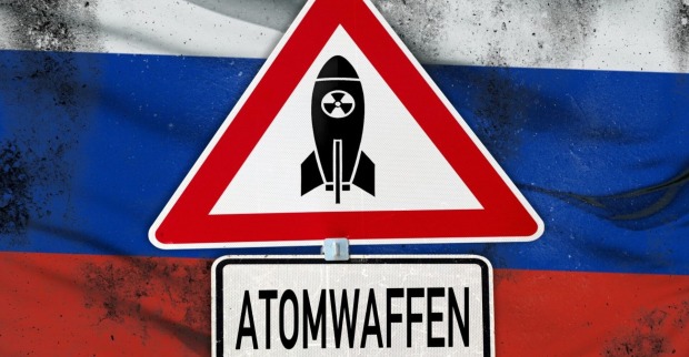 Atomwaffen, Schriftzug auf einem Warnschild mit Atombombe. Symbolbild globale Bedrohung: