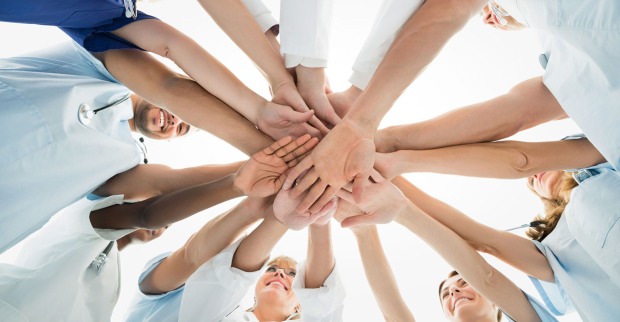 Gruppe von Menschen im Kreis, die sich an den Händen halten | Credit: iStock.com/Andrey Popov