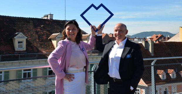 Eine Frau und ein Mann auf einer Terrasse über einer Stadt