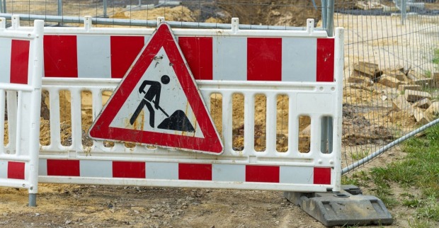 Absperrung einer Baustelle ein dreickiges Baustellenwarnschild ist auf einem Zaun angebracht