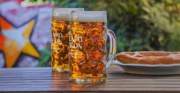 Zwei Maßkrüge mit Bier und Brezn am Holztisch