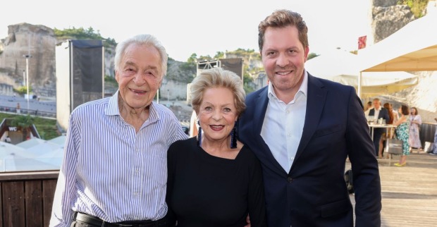 Harald Serafin steht lächelnd neben seiner Frau Ingeborg und Sohn Daniel. Im Hintergrund ist die Felsenbühne der Oper im Steinbruch St. Margarethen zu sehen.