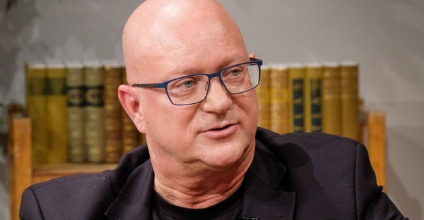Porträt von Niki Glattauer mit Brille und schwarzem Sakko, aufgenommen während eines Gesprächs vor einem Bücherregal in der Sendung "Willkommen Österreich"