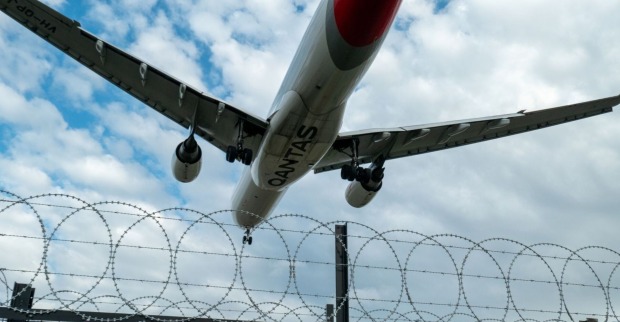 Flugzeug, welches über einem militärischen Sicherheitszaun abhebt