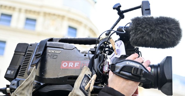Nahaufnahme einer professionellen ORF-Fernsehkamera mit Mikrofon und Handgriff während eines Außendrehs.