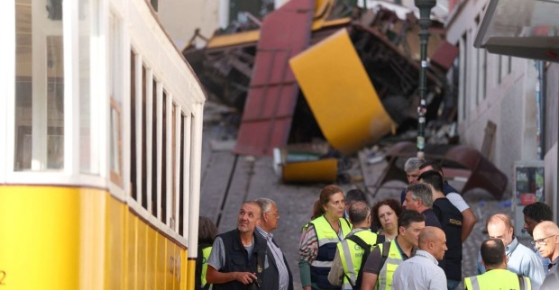 Ermittler und Einsatzkräfte stehen vor den Trümmern des entgleisten „Elevador da Glória“ in Lissabon – im Hintergrund der zerstörte gelbe Waggon.