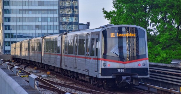 U-Bahn der Linie U1 in Wien auf oberirdischer Strecke, fährt in Richtung Leopoldau, umgeben von modernen Gebäuden und Bäumen.
