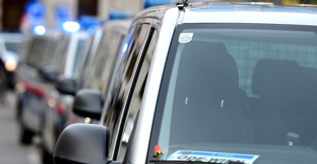 Reihe österreichischer Polizeiautos mit eingeschaltetem Blaulicht in einer Grazer Straße.