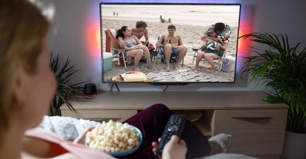 Eine Frau schaut Fernsehen und isst Popcorn