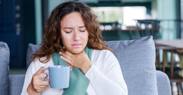 Frau greift sich an Hals | Credit: iStock.com/eternalcreative