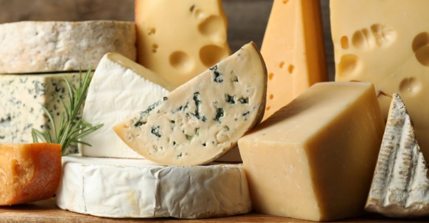 Mehrere Sorten Käse auf einem Holztisch, symbolisch für den aktuellen Metro-Rückruf von Raclette-Käse wegen Listerienverdachts.