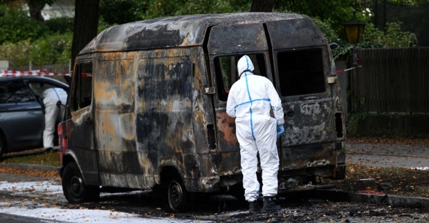 Ausgebrannter Transporter in München-Lerchenau, von Ermittlern in Schutzanzügen untersucht – Teil des Großeinsatzes nach Explosionen und Sprengfallen.