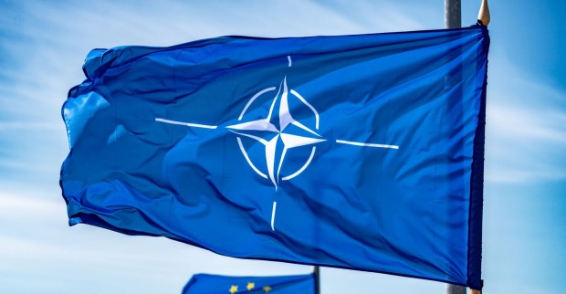 NATO-Flagge schwenkt an einem Fahnenmast im Hintergrund weht eine Flagge der Europäischen Union
