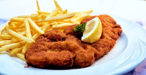 Teller mit Wiener Schnitzel, Zitronenspalte und Pommes frites, traditionelles österreichisches Gericht wie es auch  im Thomawirt serviert wird.