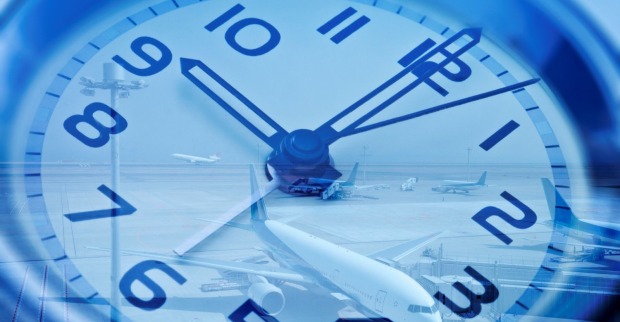 Symbolfoto: Große Uhr mit Blick auf Flugzeuge am Flughafen, Sinnbild für Jetlag und Zeitverschiebung.
