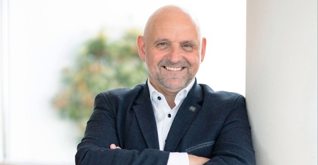 Ein lächelnder Mann mit verschränkten Armen