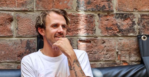 Ein junger Mann in weißem Shirt blickt nachdenklich drein