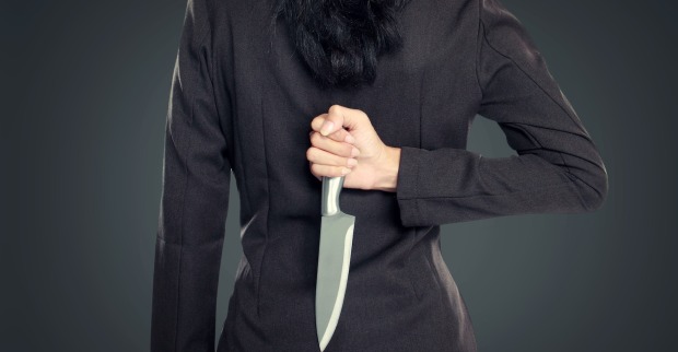 Frau in Kostümjacke von hinten mit Messer in der Hand