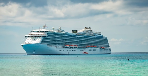Großes Kreuzfahrtschiff auf türkisblauem Meer unter bewölktem Himmel, Symbolbild für den Fall der auf See verstorbenen 18-jährigen Passagierin.