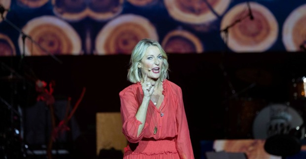 Monika Gruber in rotem Kleid auf der Bühne.