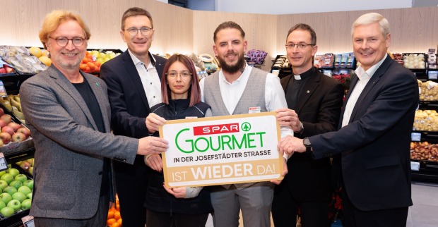 Sechs Personen halten in der Spar-Filiale ein Spar-Gourmet-Schild